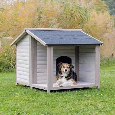 Niche pour chien en bois avec toit gris et porte d'entrée ouverte, placée sur une pelouse verte.