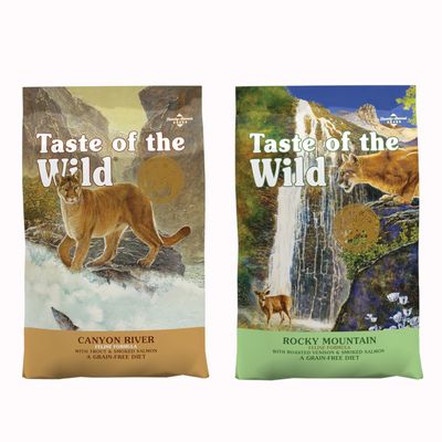 Dos sacos de pienso Taste of the Wild con imágenes de animales y naturaleza en el envase. Símbolo de porcentaje rojo indica oferta o descuento.