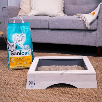Sanicat Clumping cat litter, 10L, unscented, with oxygen control. Shown next to a wooden cat toilet with grey insert.
