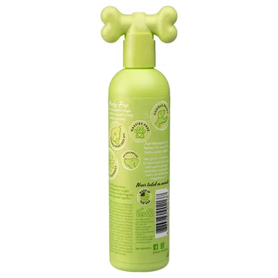 Grøn flaske med knogleformet pumpe. Synlig tekst: 'Prickly Pear Oil', 'pH Balanced', 'Cuddle Ready', 'Nasties Free', 'Never tested on animals', 'Made in the USA'. Stregkode og symboler.