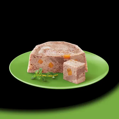 Pasticcio di carne con pezzi arancioni su piatto verde, decorato con erbe fresche.