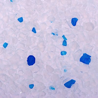 Close-up van witte en blauwe silica kattenbakvulling korrels, geen merknaam zichtbaar.