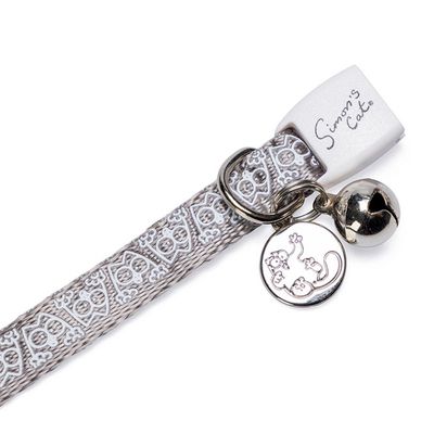 Collier pour chat gris avec motifs blancs, clochette argentée et fermoir marqué « Simon's Cat » visible sur l’étiquette.