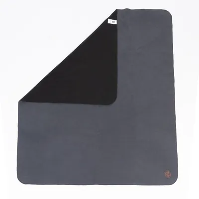 Grey and black blanket with rounded corners, logo in the bottom right corner and label visible in the top left.