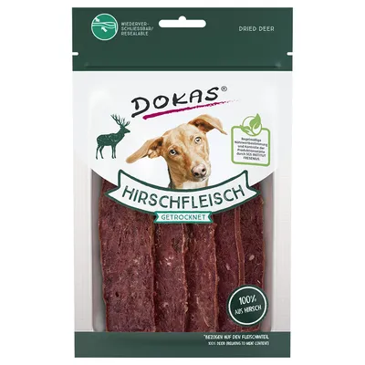 Pachet Dokas cu carne uscată de cerb, text vizibil: HIRSCHFLEISCH GETROCKNET, 100% aus Hirsch, imagine câine și simbol cerb, ambalaj resigilabil.