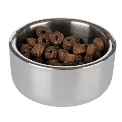 Hopea ruokakuppi, täytetty ruskeilla, renkaanmuotoisilla kuivaruokapaloilla.