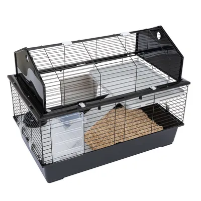 Cage pour rongeur en métal et plastique noir, avec étage intérieur blanc, porte latérale transparente et litière visible au fond.