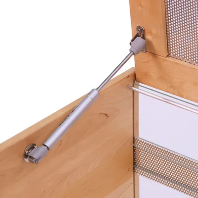Close-up view of a wooden cabinet with gas strut and metal grid insert. Shows the attachment of the strut to the cabinet.