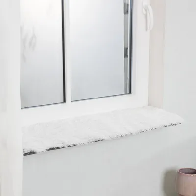 Obdélníková podložka na parapet z bílého umělého kožíšku, vhodná pro dekoraci nebo pohodlné použití.