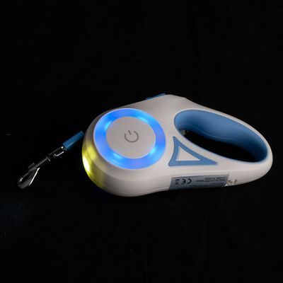 Weisse und blaue Hundeleine mit LED-Beleuchtung, Ein-/Ausschalter-Symbol und CE-Kennzeichnung. Metallclip zur Befestigung sichtbar.