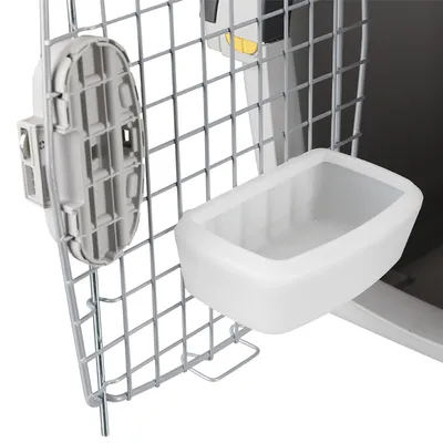 Vedere detaliată a unei cutii de transport cu ușă din grilaj metalic și bol din plastic alb atașat de ușă. Vedere detaliată a unei cutii de transport cu ușă din grilaj metalic și bol din plastic alb atașat de ușă.