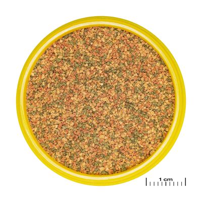 Närbild av färgglatt granulatfoder i en gul behållare, med måttskala för storleksjämförelse (1 cm).