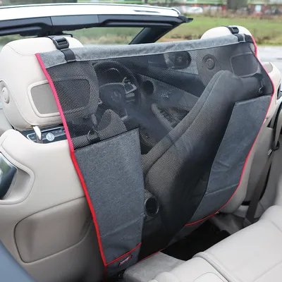 Grille de séparation en tissu et maille noire fixée entre les sièges avant d’une voiture, avec bordure rouge et poches latérales visibles.