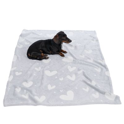 Graue Decke mit weissen Herzmustern, darauf liegt ein kleiner schwarzer Hund. Produkt zur Nutzung als Haustierdecke sichtbar.