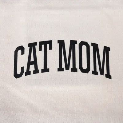 Nápis 'CAT MOM' černými velkými písmeny na bílém textilu.