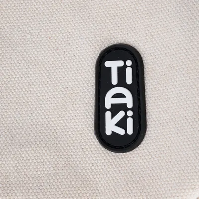 Tiaki. Značka pro produkty pro domácí mazlíčky, logo na béžovém textilním pozadí.