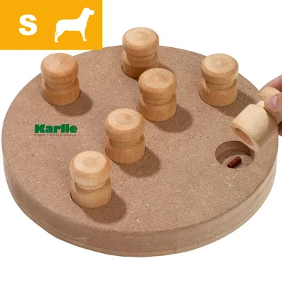 Rundt trælegetøj med otte trækugler, en hånd løfter én og afslører godbid. Synligt mærke: Karli. Gul felt med S og hundesilhuet øverst til venstre.
