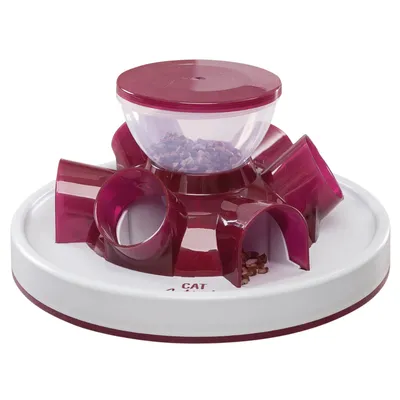 Comedero interactivo para gatos de plástico, con compartimentos y túneles en color burdeos y base blanca. El recipiente superior contiene croquetas visibles.