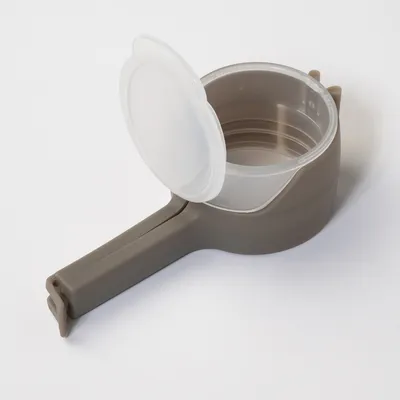 Measuring cup made of plastic with grey handle and transparent lid, suitable for measuring liquids or food.