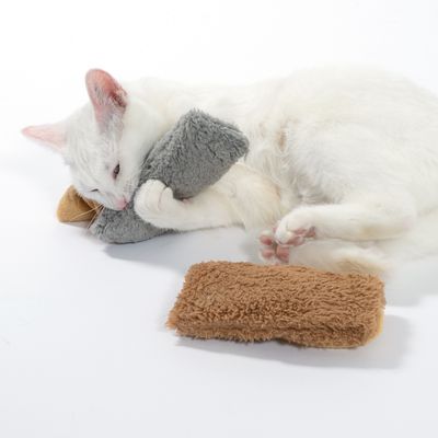 Белая кошка играет с серой и коричневой плюшевой игрушкой. Показывает использование мягкой игрушки для кошек.