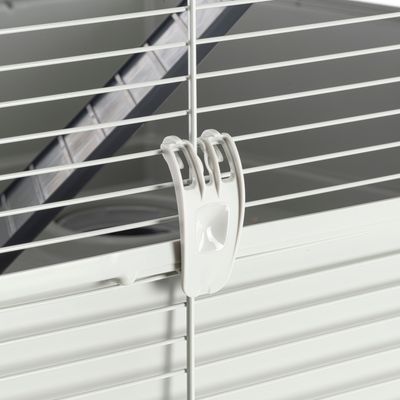 Крупный план белого пластикового зажима для фиксации решетчатой двери на клетке для мелких животных.