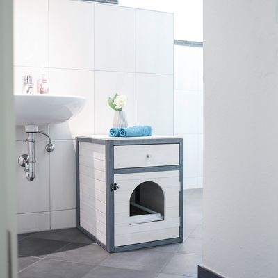 Meuble en bois blanc et gris avec tiroir, porte à ouverture arrondie et poignée, placé dans une salle de bain sous un lavabo. Deux serviettes bleues et un vase sont posés dessus.