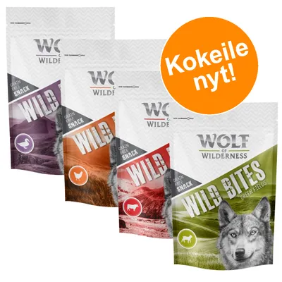 Wolf of Wilderness Grain Free Snack WILD BITES -koiranherkkupusseja eri makuja, pakkauksissa eläinsymbolit. Oranssi ympyrä: Kokeile nyt!