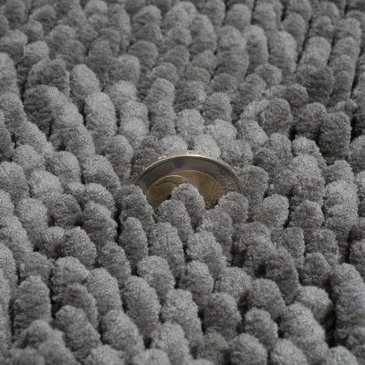 Close-up of a grey carpet with dense texture, a coin shows the height of the fibres.