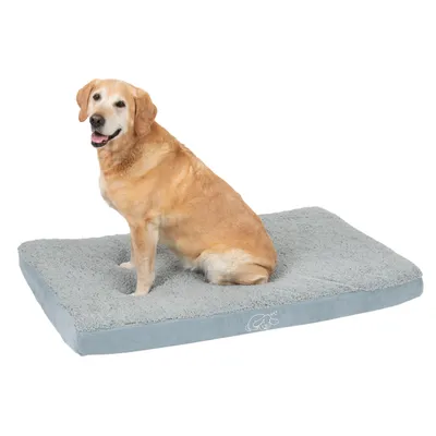 Hund sitter på en grå, rektangulär hundsäng med mjuk yta och logotyp i hörnet.