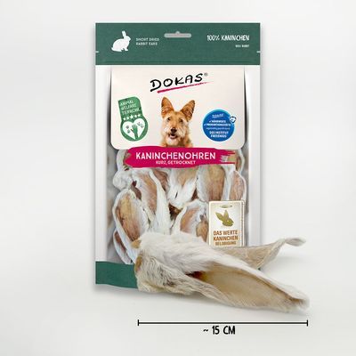 DOKAS Kaninchenohren, kurz, gedroogd. Verpakking met afbeelding van hond en zichtbare konijnenoren. Tekst: 100% Kaninchen, Das wertet Kaninchen vollständig biologisch. Lengte ~15 cm.