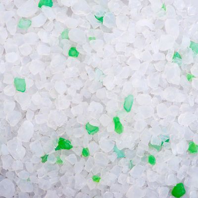 Weiße, grobkörnige Kristalle mit vereinzelten grünen Stücken, Nahaufnahme des Produkts.