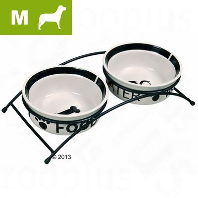 Kaksi keraamista koiran ruokakuppia metallitelineessä, vasemmassa kupissa teksti FOOD ja oikeassa WATER. Vasemmassa yläkulmassa M-koko ja koiran siluetti.