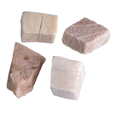 Quattro cubetti di snack per animali, colore beige e marrone chiaro, superficie porosa, senza confezione visibile o marchio.