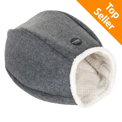 Cuccia a forma di grotta in tessuto grigio con interno bianco, etichetta visibile 'Cosma pure Love', angolo arancione con testo 'Top Seller'.