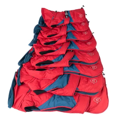 Gamme de manteaux pour chien rouges et bleus, plusieurs tailles empilées, logo NT visible sur chaque manteau.