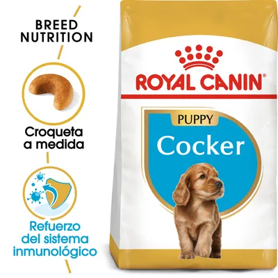 Saco de pienso Royal Canin Puppy Cocker. Texto visible: 'Croqueta a medida', 'Refuerzo del sistema inmunológico', 'Breed Nutrition'. Imagen de croqueta y escudo con virus.