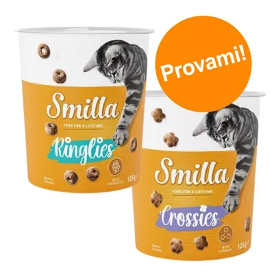 Due confezioni di snack per gatti Smilla, varianti Ringlies e Crossies da 125 g, con scritte 'with prebiotics' e 'with vitamins'. Bollino arancione con testo: Provami!