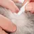 Person parting animal fur and applying liquid from a small tube directly onto the skin, demonstrating topical application method.