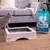 Sanicat Clumping cat litter, 10L pack next to a wooden cat toilet with grey insert. Cat standing beside it on carpet.