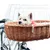 Cykelkorg av flätat trä med vitt metallgaller, monterad på en cykel. En liten hund sitter i korgen och har en röd halsduk.