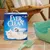 Ever Clean kattenbakvulling verpakking naast groene kattenbak en schep. Verpakking toont witte kat, merknaam en pictogrammen voor producteigenschappen.