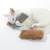 Gato blanco juega con juguete de peluche gris y marrón. El producto muestra el uso de un juguete suave para gatos.