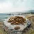 Hundefutter in Krokettenform, Grösse 14-16 mm, auf einem Stein präsentiert mit Landschaft im Hintergrund.