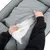 Mani che aprono la fodera di un cuscino o letto per animali in tessuto grigio, mostrando l'interno imbottito con materiale bianco visibile.