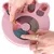 Pink interactive toy with compartments that open by sliding. Hands place treats into the compartments.