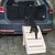 Hund steigt über eine beige Kunststoff-Hundetreppenhilfe in den Kofferraum eines Autos. Treppe mit vier Stufen und rutschfesten Belägen.