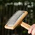 Wooden brush with metal bristles, suitable for removing pet hair. Shows a hand holding the brush with hair between the bristles.