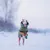 Chien portant un manteau vert à capuche, courant dans la neige. Le manteau couvre le corps et les pattes avant du chien, matériau semblant imperméable.