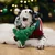 Dog with a green fabric toy in the shape of a Christmas tree, lying on a white carpet. The toy features colourful dots and zigzag lines. Dog with a green fabric toy in the shape of a Christmas tree, lying on a white carpet. The toy features colourful dots and zigzag lines.