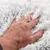 Hand berührt weiches, flauschiges Material in weiss und grau. Zeigt die Textur des Produkts.